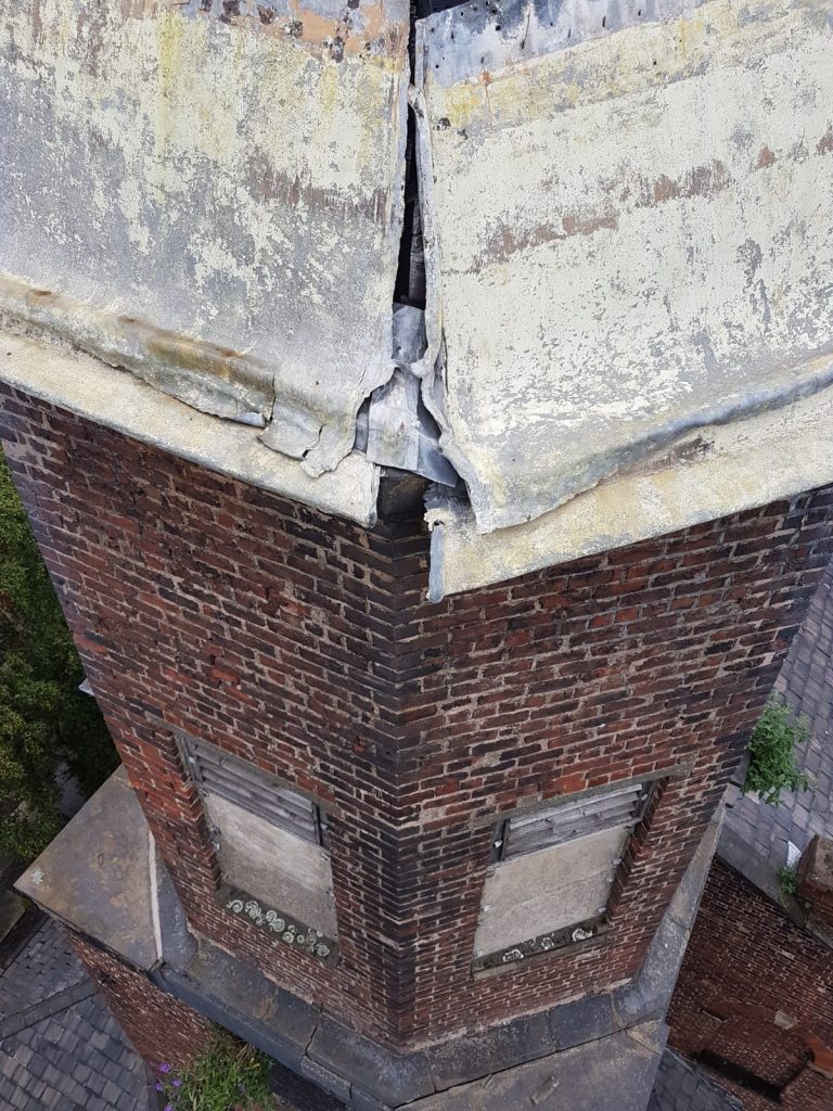 A large crack in th eroof plate is visible atop the brick tower