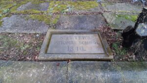 The large stone in situ which reads 'St Peter's National School 1844'