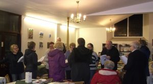 Twelve singers stood up with song sheets having a jolly singalong!